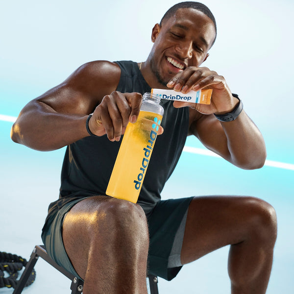 Man holding a DripDrop bottle and packet against a light blue background