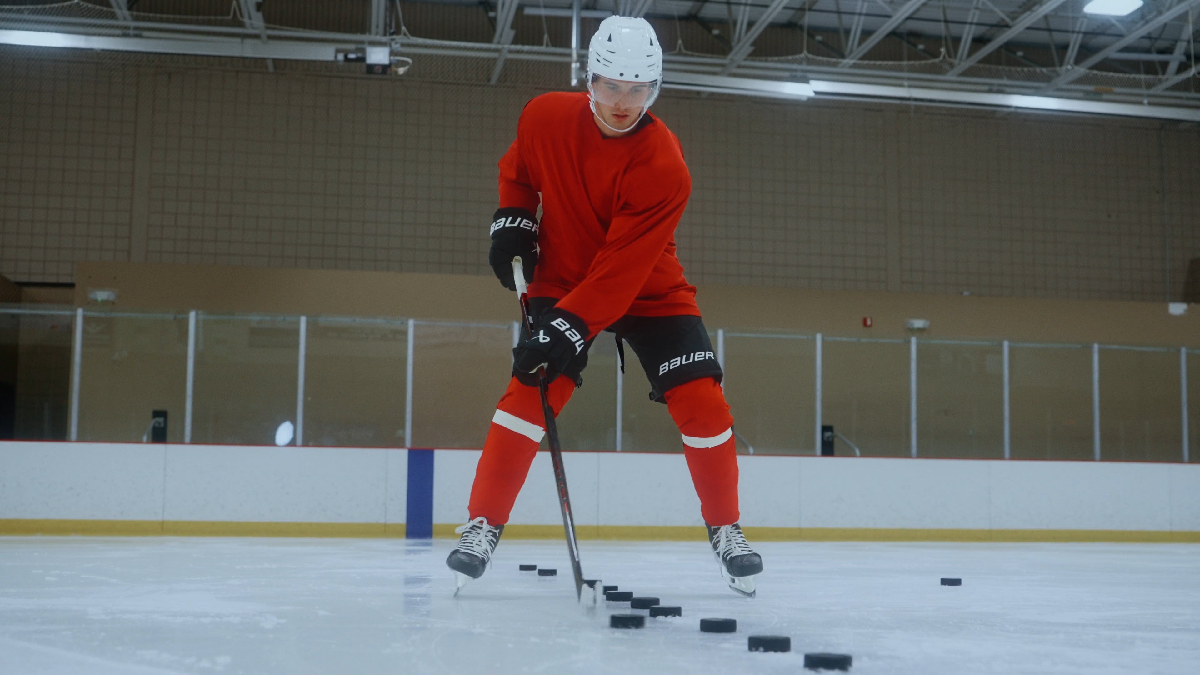 Jack Hughes in red hockey gear on an indoor ice rink