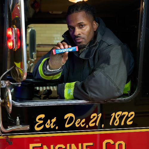 Man in a fire truck holding a stick of DripDrop