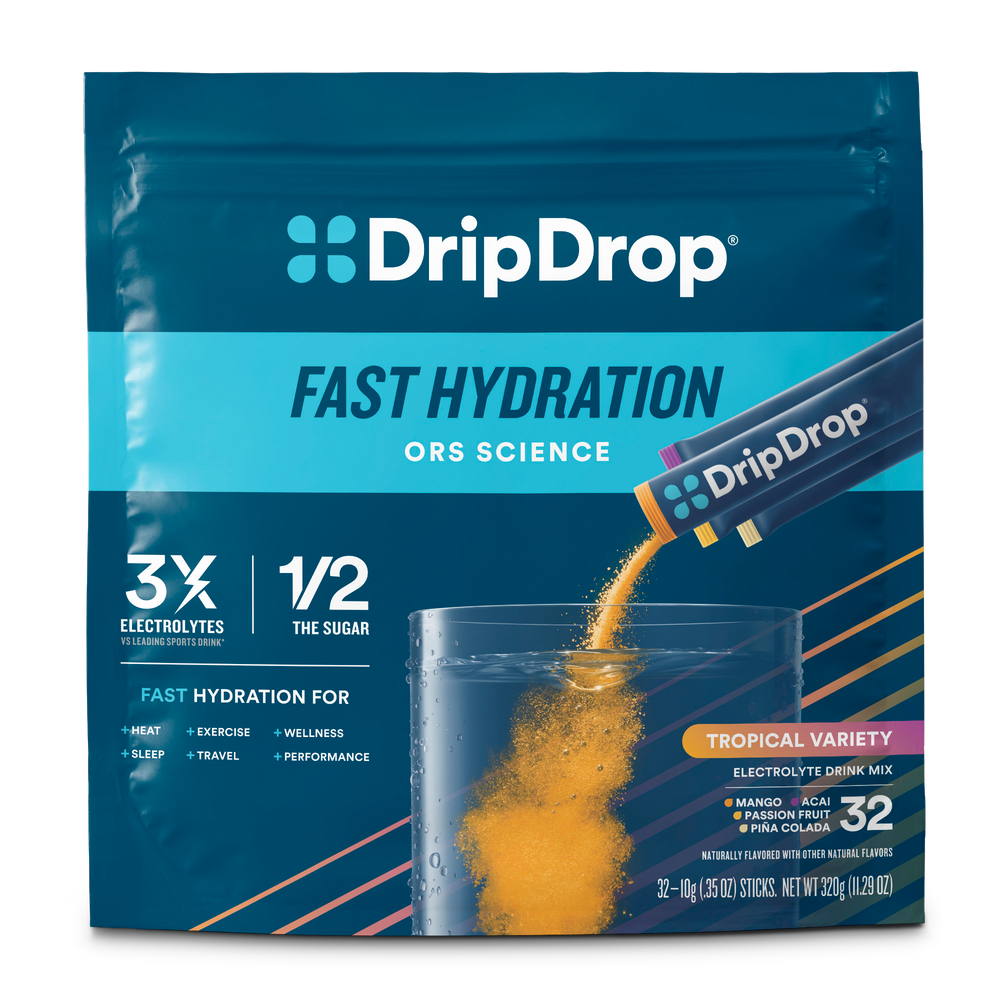 A package of DripDrop Fast Hydration electrolyte drink mix in Tropical Variety. The pouch is dark blue with a cyan band and shows an orange powder mix being poured into a clear glass of water.
