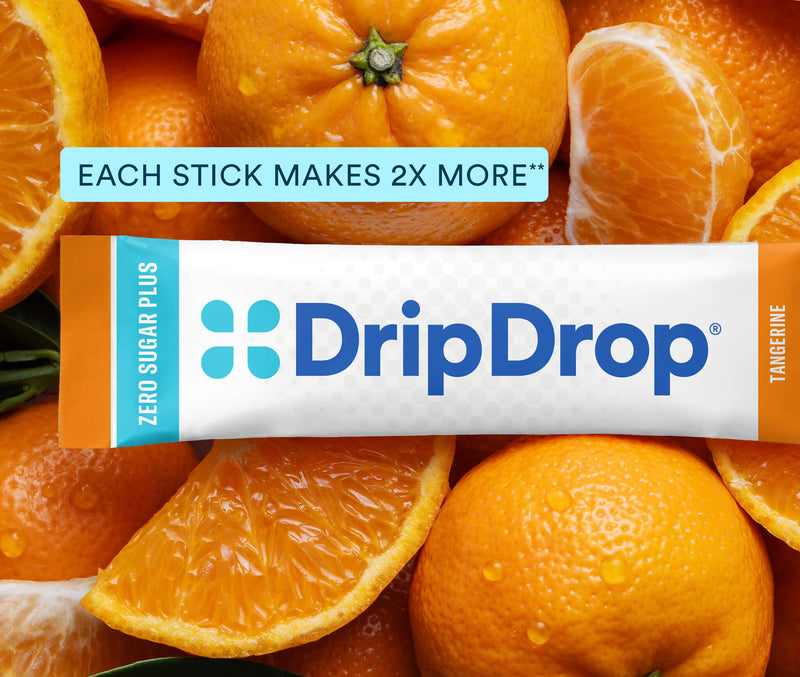 A DripDrop Zero Sugar Plus stick pack for Tangerine flavor, shown horizontally over a close-up background of sliced oranges and orange pulp. The package is white with blue branding and orange side accents.