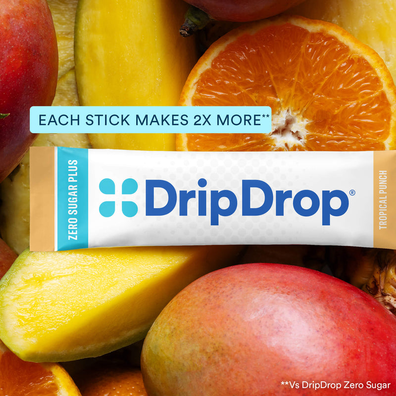 A DripDrop Zero Sugar Plus Tropical Punch flavored stick is centered over a close-up background of sliced mangoes and orange fruit. Text on the image reads 'EACH STICK MAKES 2X MORE' and 'DripDrop' branding is clearly visible on the stick packaging.