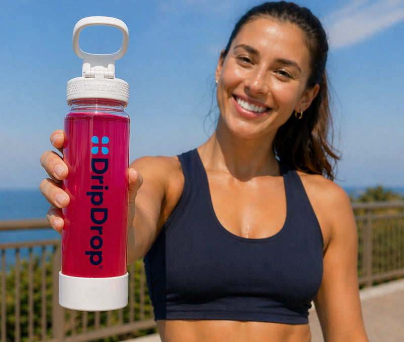 Woman holding a pink DripDrop water bottle outdoors with a blue sky background