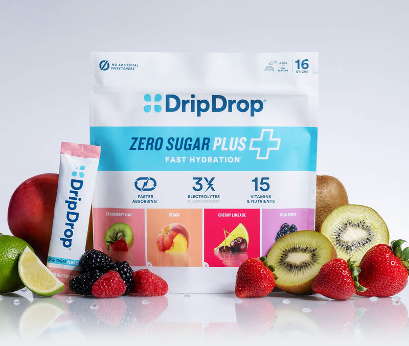 A stand-up pouch of DripDrop Zero Sugar Plus fast hydration powder, shown with a smaller single-serve stick pack in front. The package is white and light blue with colorful fruit flavor panels, surrounded by fresh strawberries, kiwi, blackberries, raspberries, a lime, and a red apple on a clean white studio background.