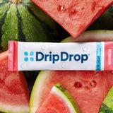 A DripDrop Zero Sugar Plus+ watermelon flavor stick pack, placed horizontally over a close-up background of fresh watermelon slices.