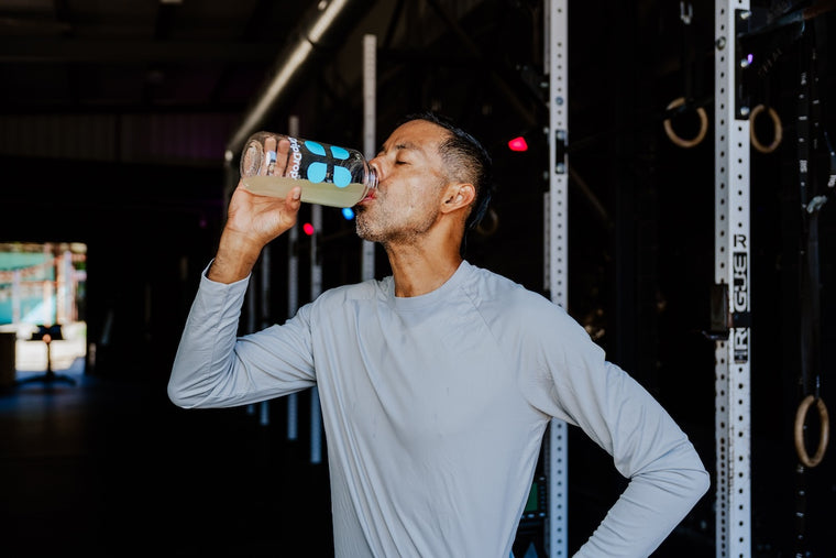 Man drinking from a water bottle in a gym setting
