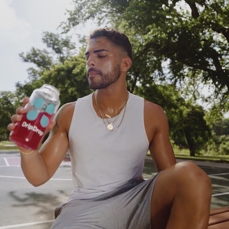 Man drinking red liquid from a water bottle on a basketball court
