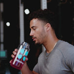 Man drinking pink liquid from a water bottle